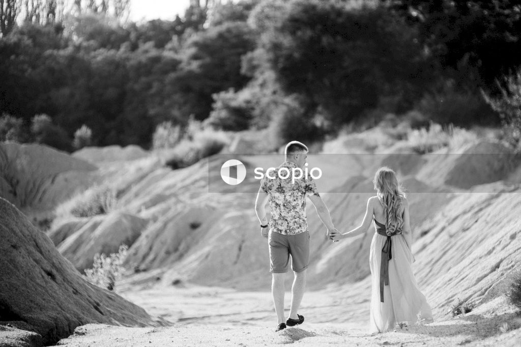 Grayscale photo of couple walking on sand