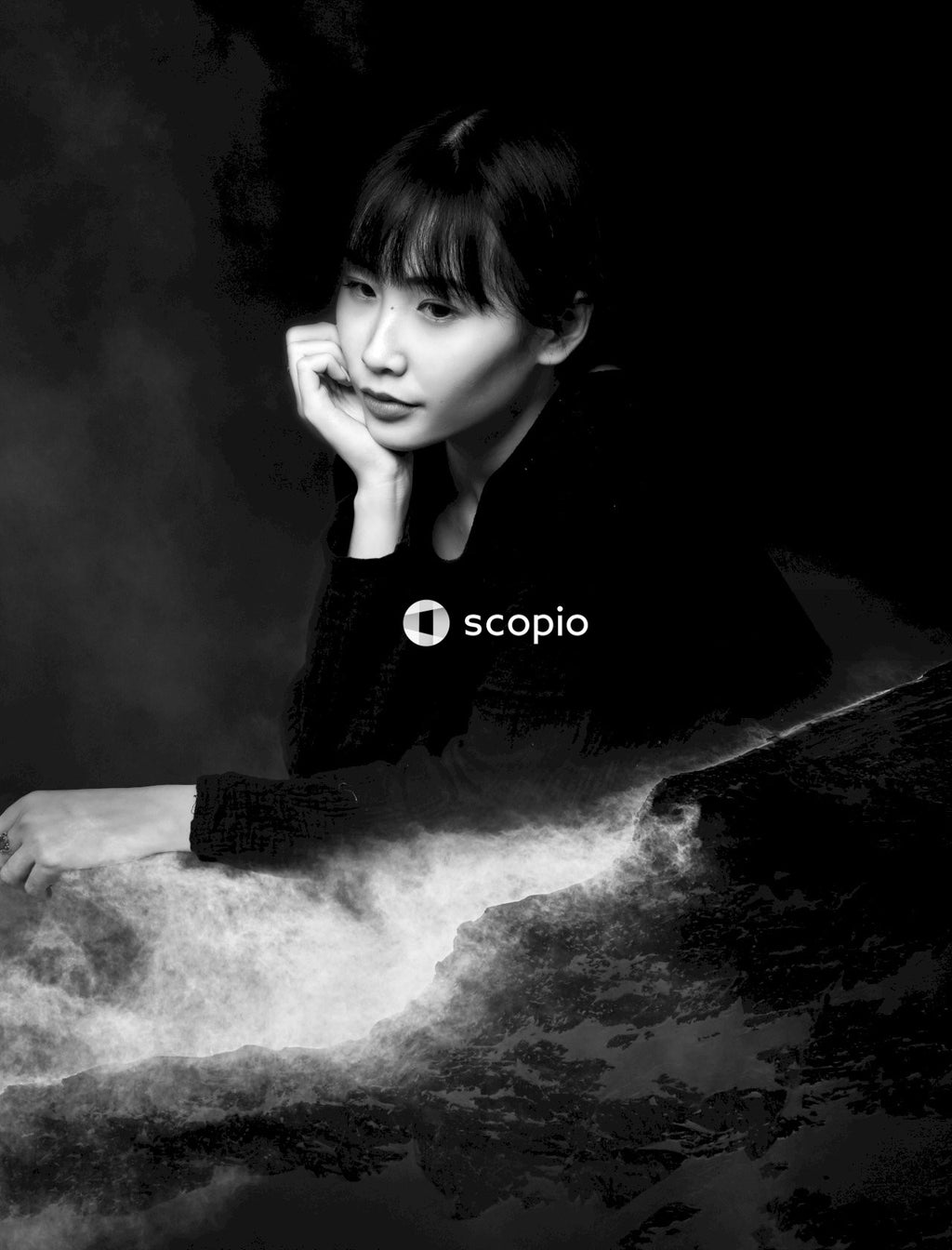 Grayscale portrait of Asian looking model resting chin on hand