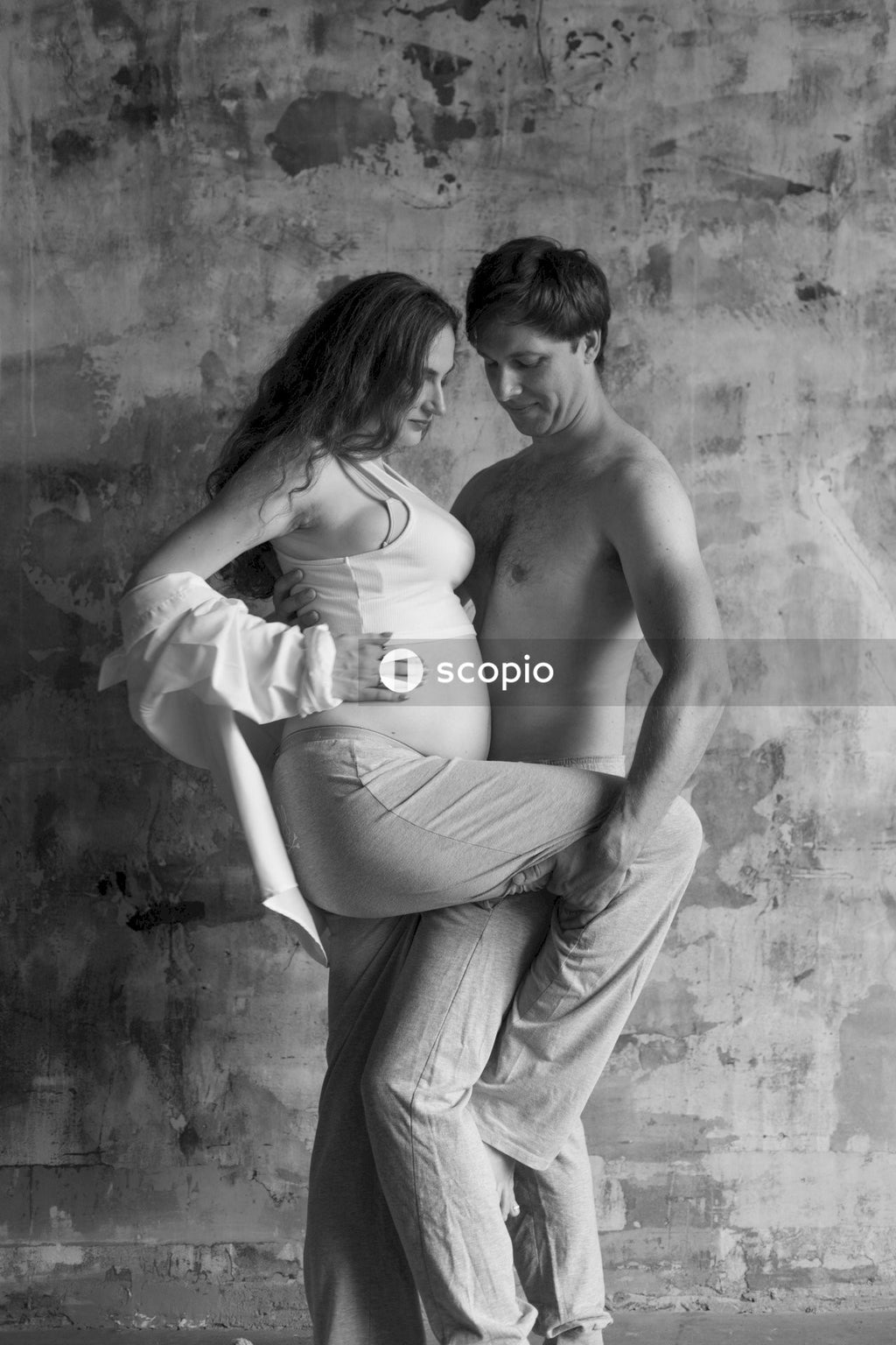 A Grayscale photo of a man and a pregnant woman hugging