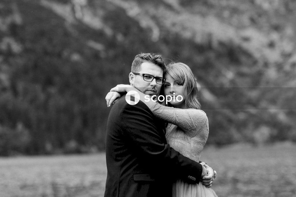 Grayscale photo of man hugging woman