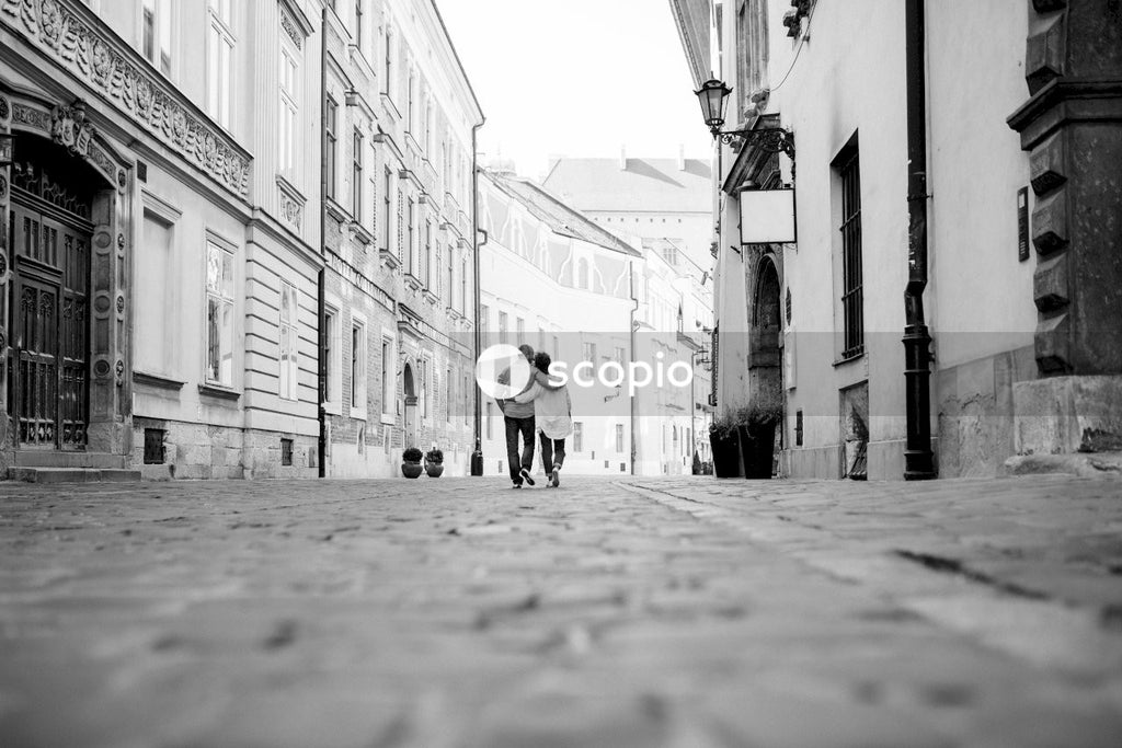 Grayscale photo of man and woman walking on street
