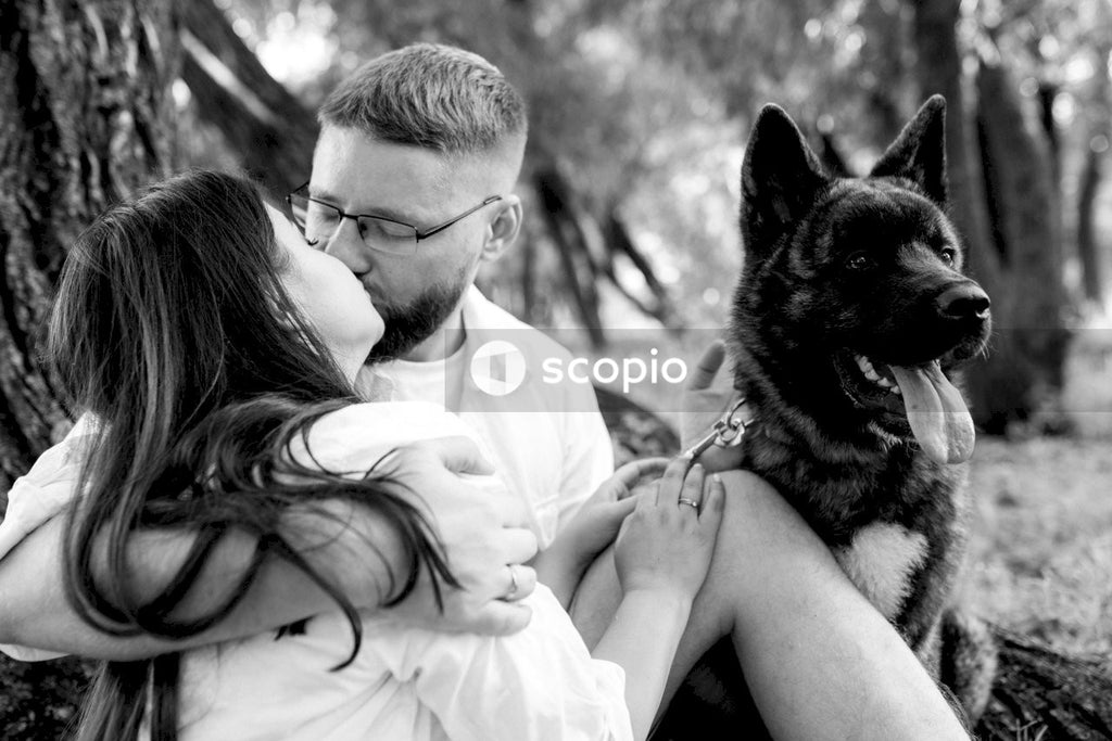 Grayscale photo of woman in dress shirt holding german shepherd