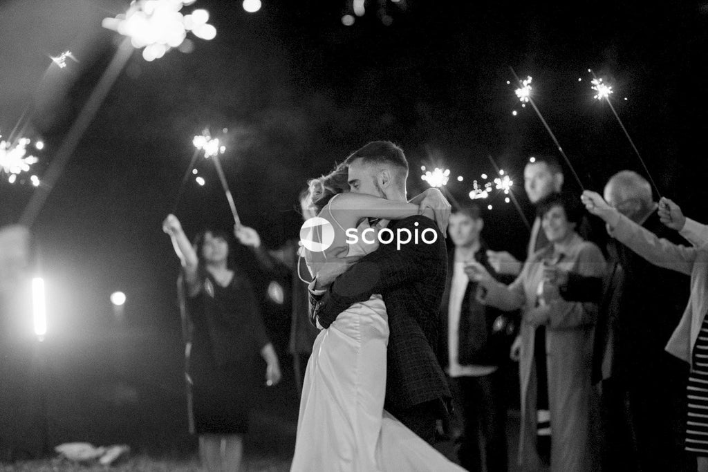 Grayscale photo of woman in white dress hugging man in black suit