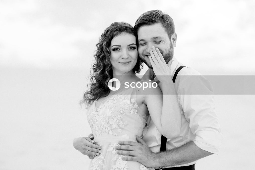 Grayscale photo of woman in white dress hugging woman in white dress