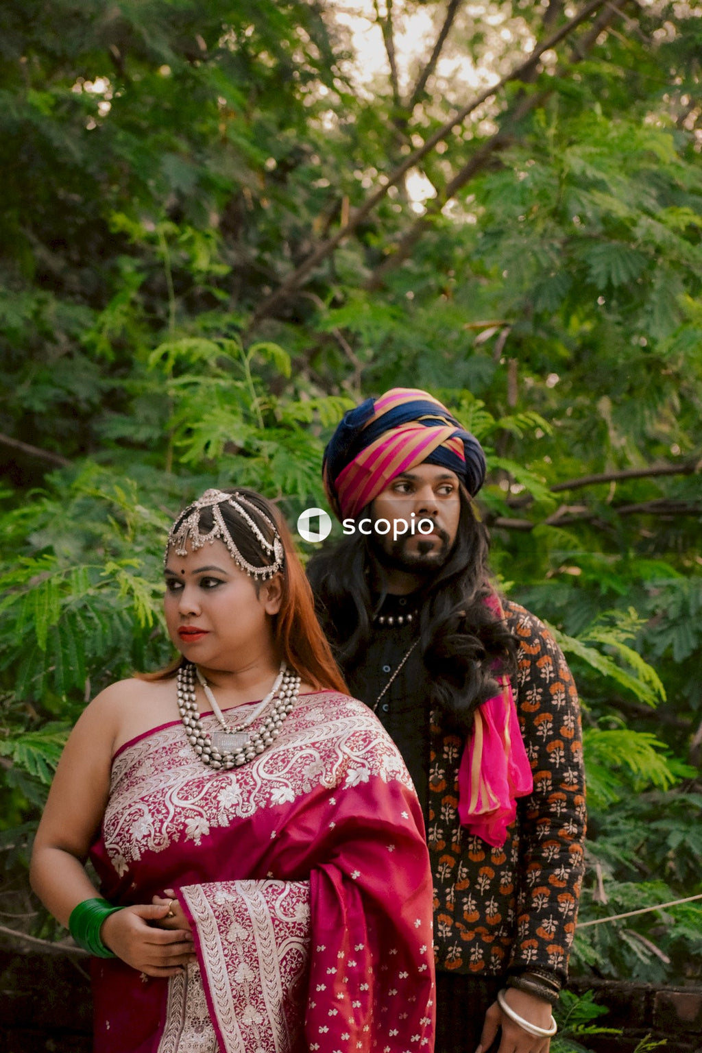 Indian woman in pink saree standing beside a man wearing turban