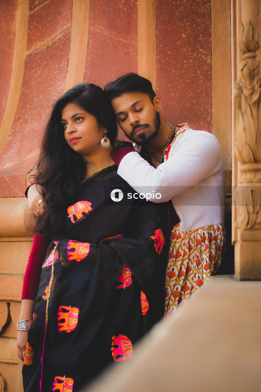 Man and woman hugging beside building