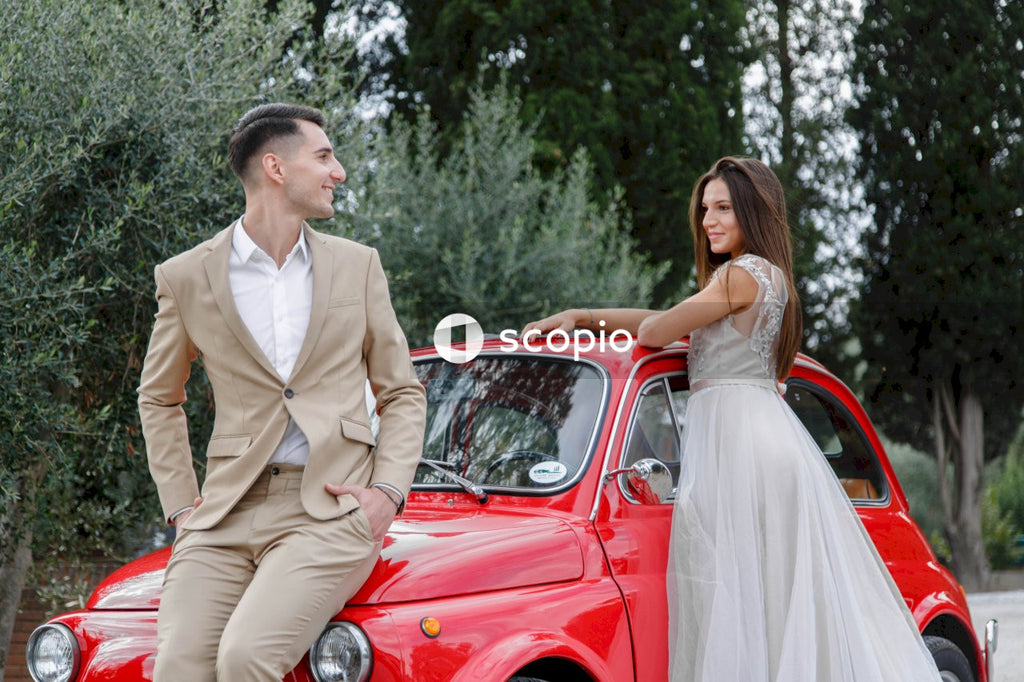 Young married couple doing a photoshoot near small red car