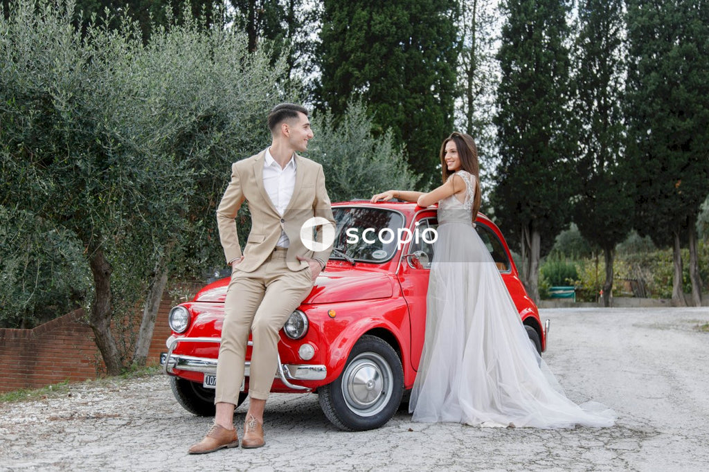 Young married couple doing a photoshoot near small red car