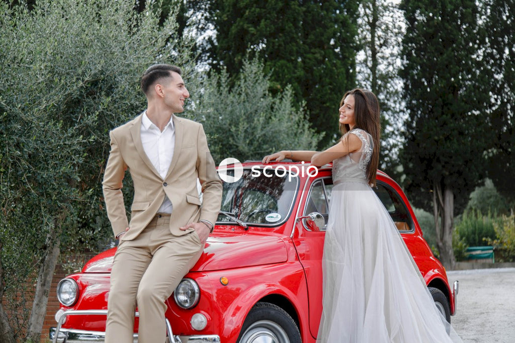 Young married couple doing a photoshoot near small red car