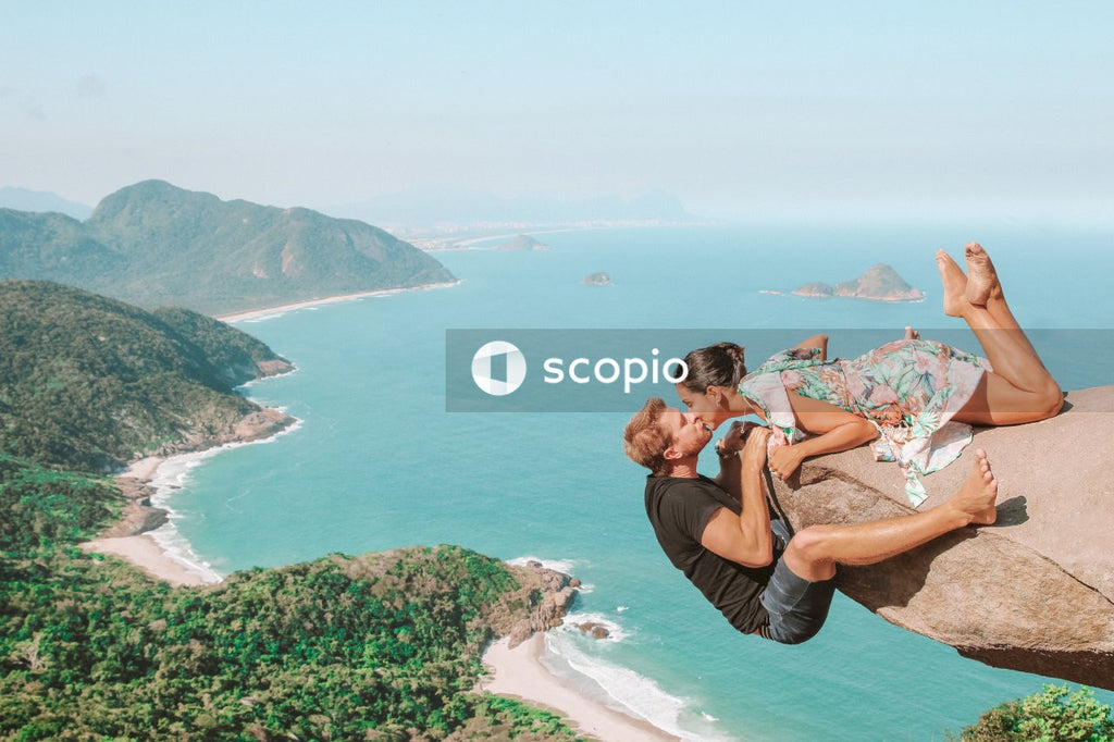 Man and woman kissing at the edge of cliff above the coast