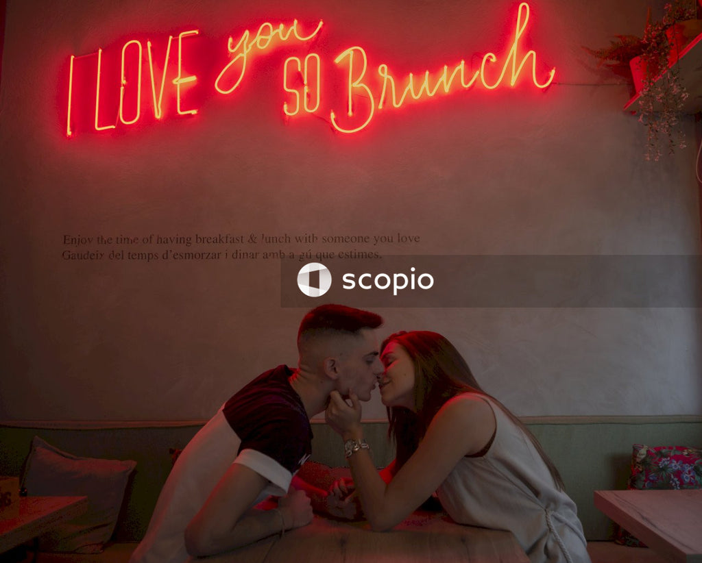 Man and woman kissing under "i love you so brunch" red led light