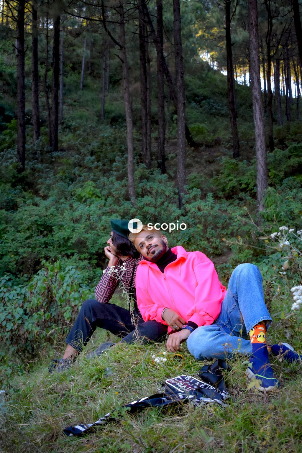 Two gay men in casual outfit sitting grass field near woods