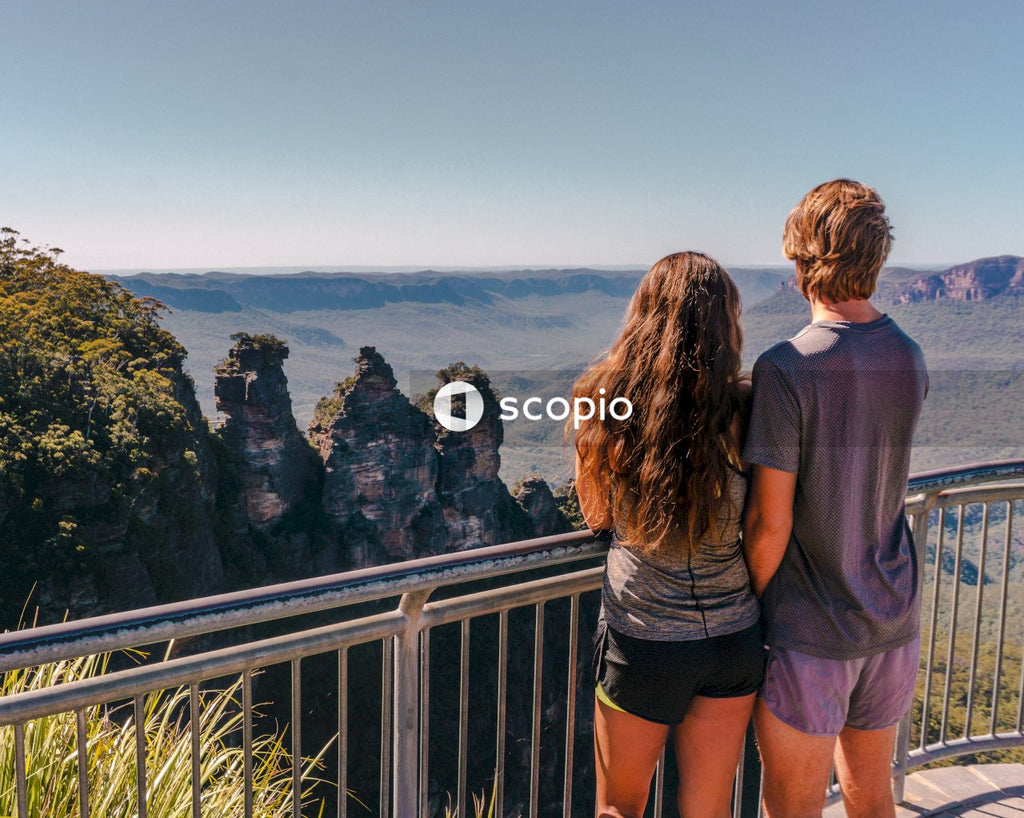 Man and woman standing at fence looking at ocean view
