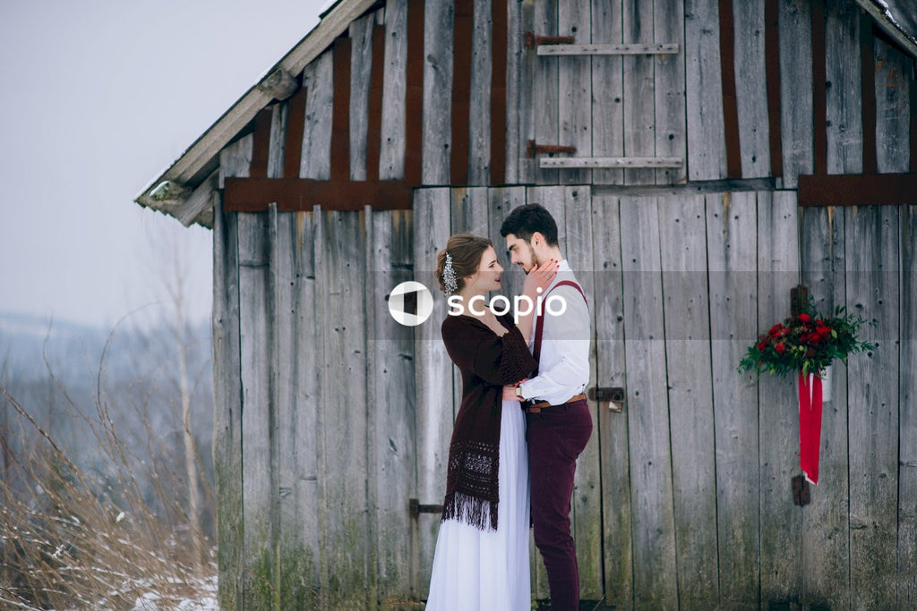 Man and woman standing beside brown wooden house
