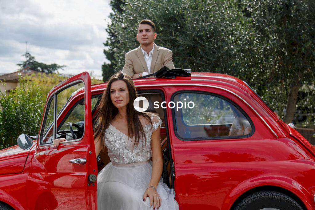 Young married couple doing a photoshoot near small red car
