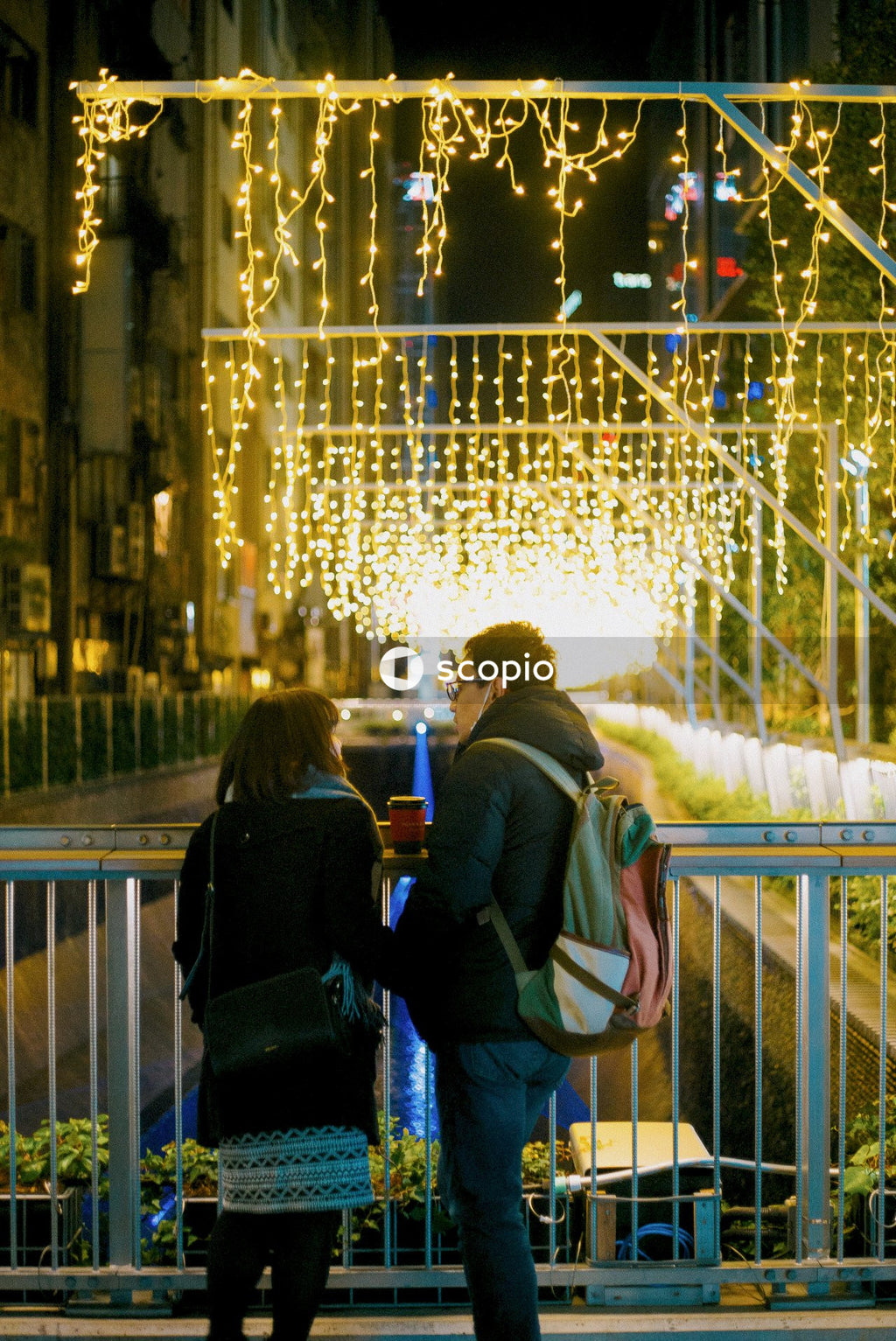 Back view of man and woman standing on street during night time