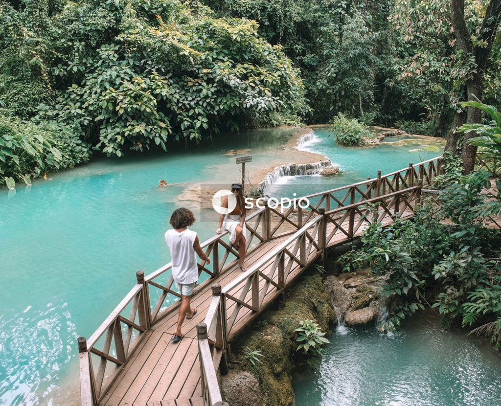 Man and woman standing on wooden bridge above river