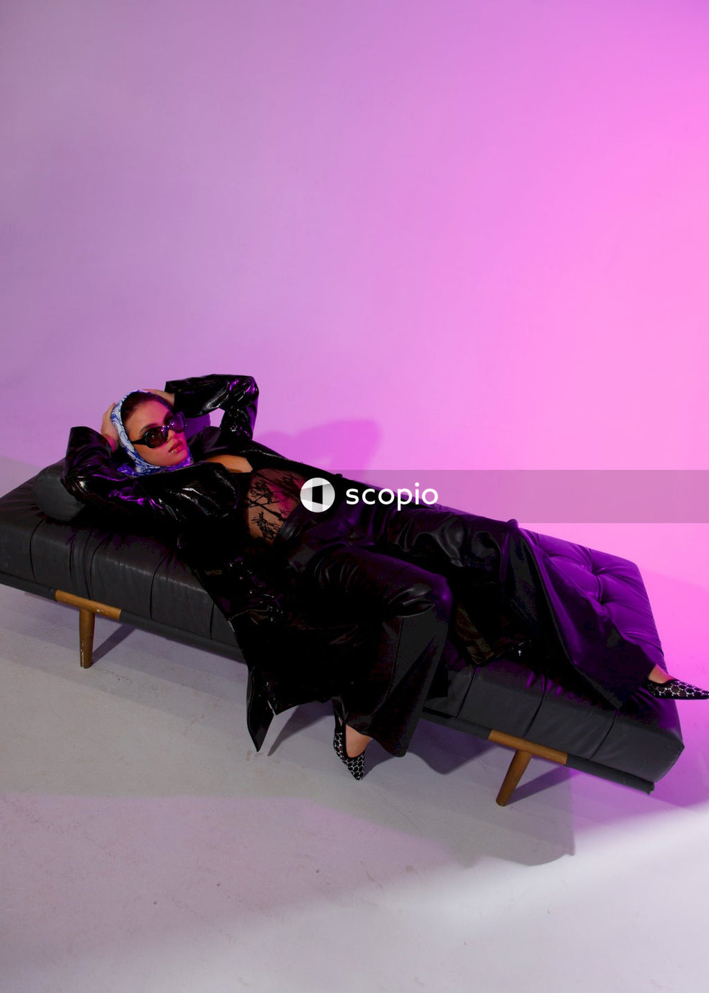 Man in black and brown robe lying on purple couch