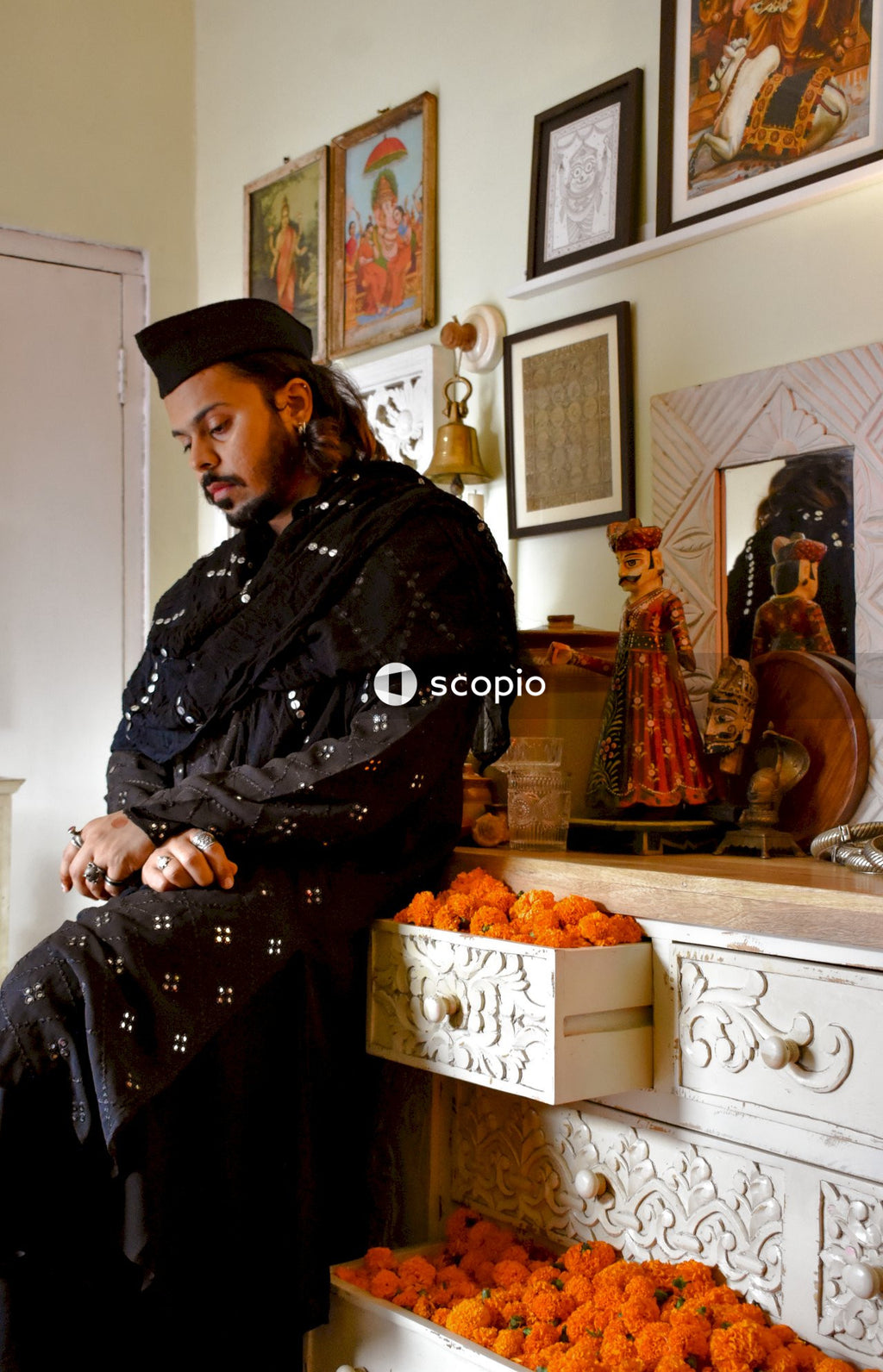 Man in black and gray robe sitting on brown wooden chair