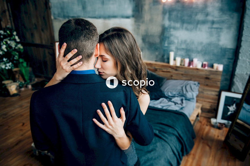 Man in black crew neck shirt hugging woman in blue long sleeve shirt