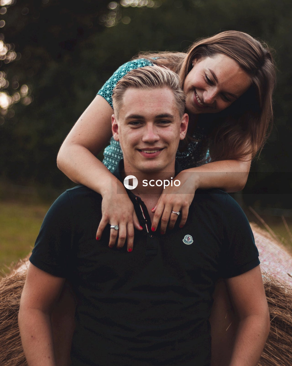 Man in black crew neck t-shirt hugging woman in blue and white floral dress