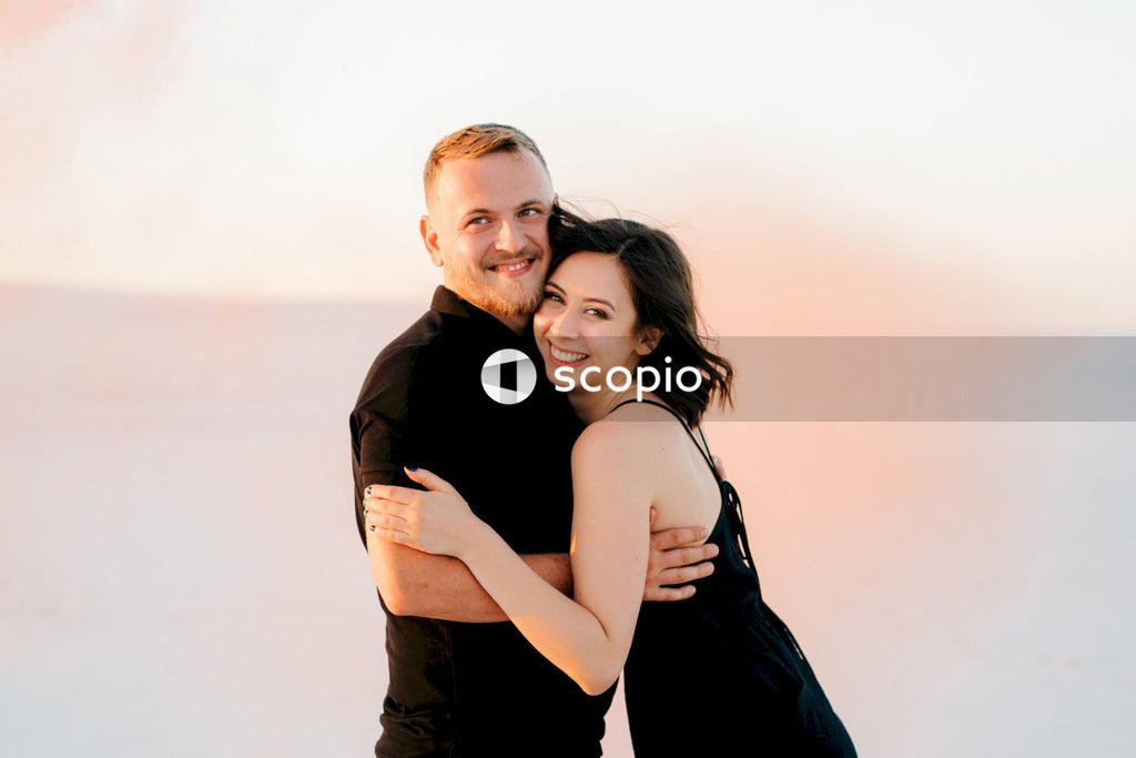 Man in black dress shirt hugging woman in black sleeveless dress