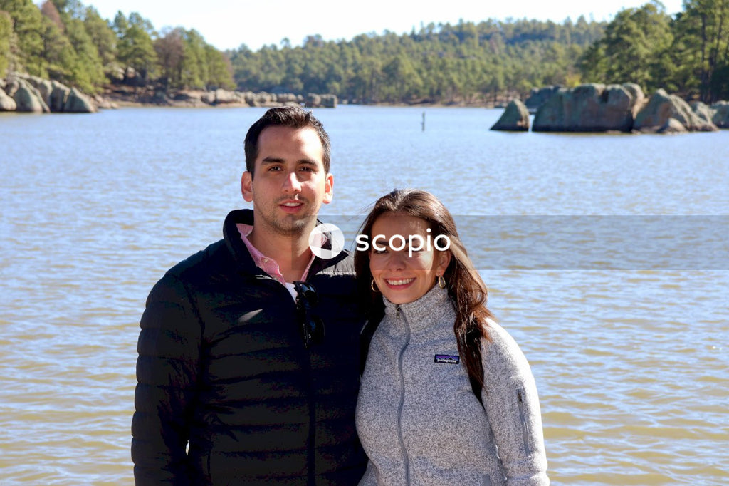 Man and woman wearing jacket standing side by side near lake