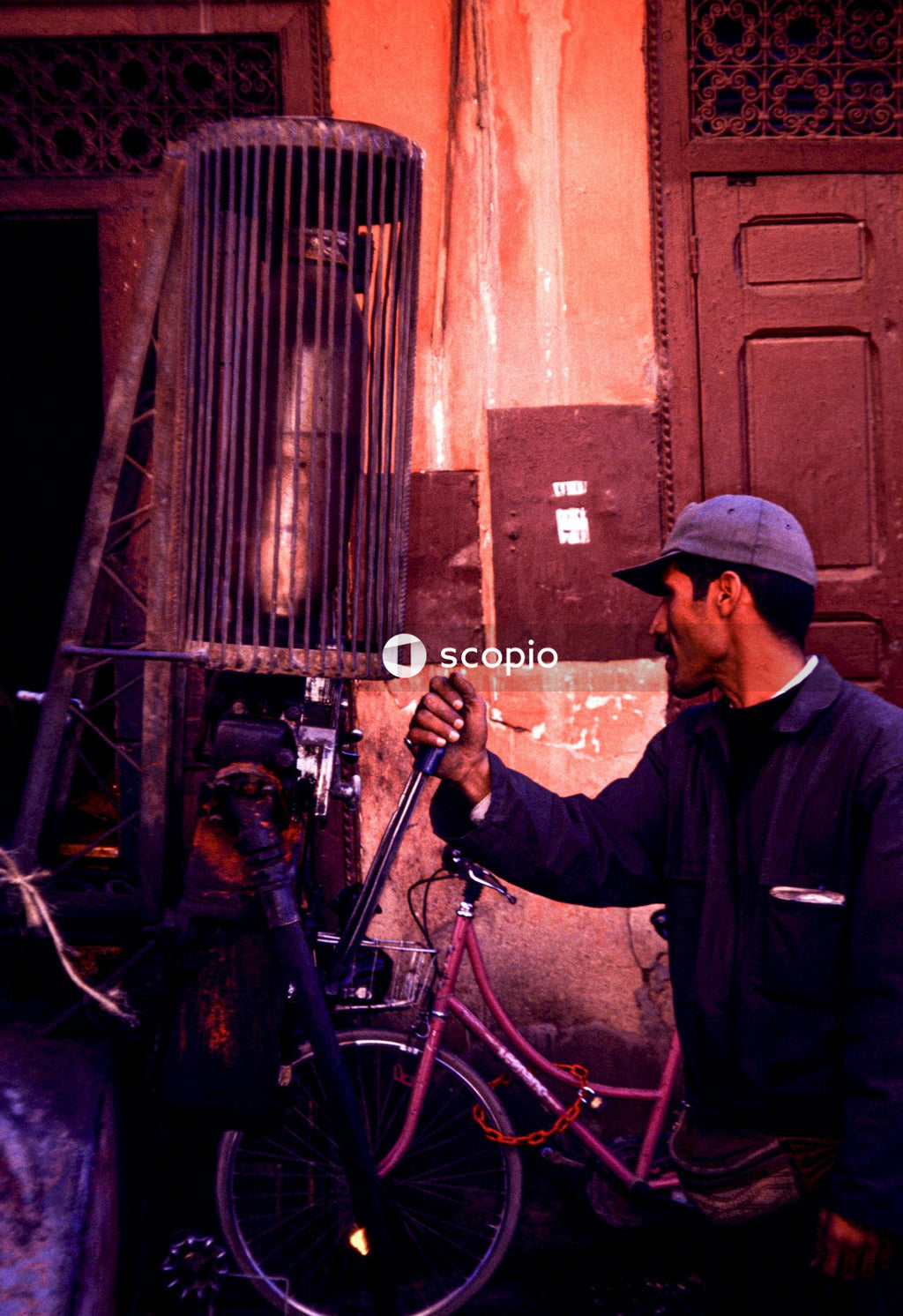 Man in black jacket holding red bicycle
