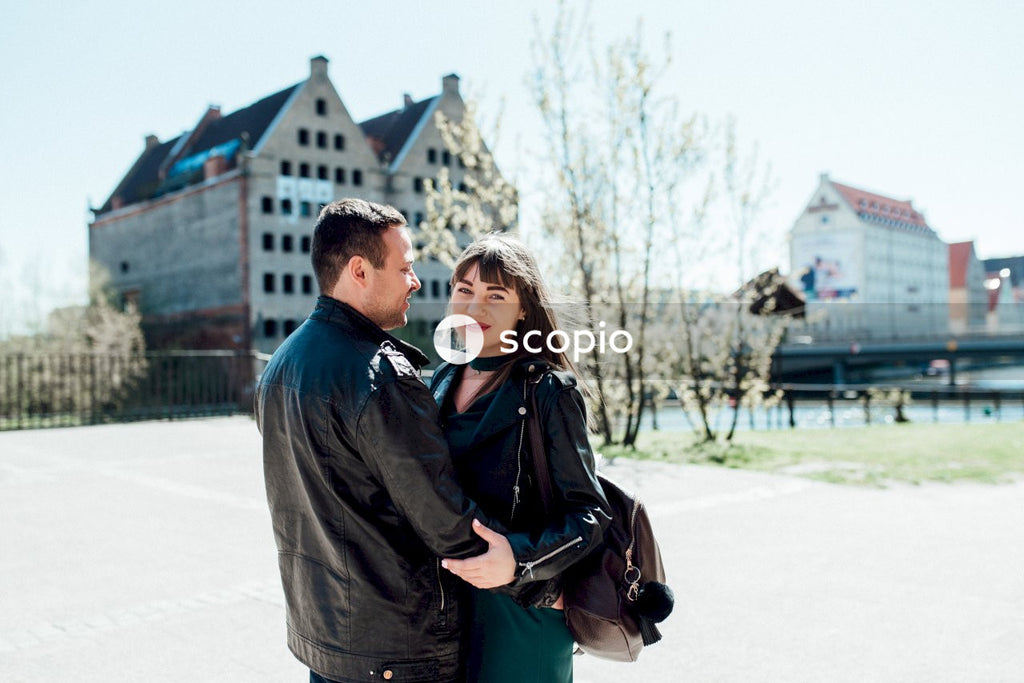 Man in black jacket hugging woman in green coat
