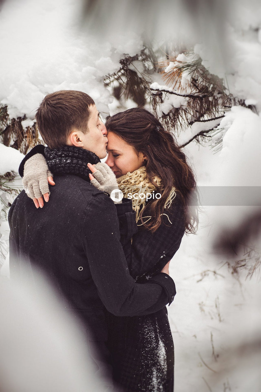 Man in black jacket hugging woman in white and black scarf