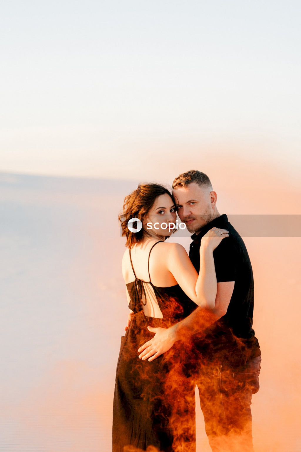Man in black jacket hugging woman in white tank top