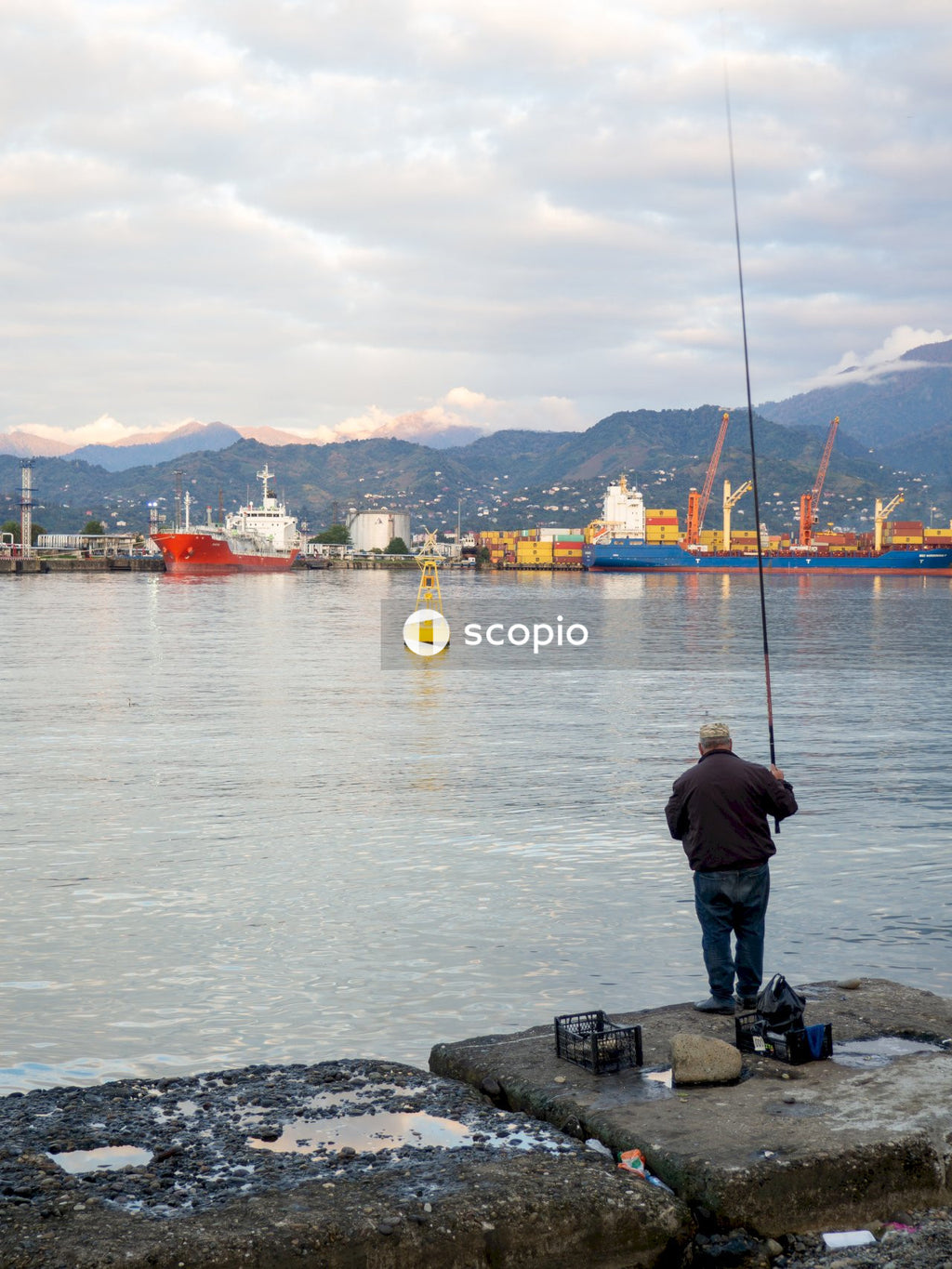 Man in black jacket standing on rock near body of water