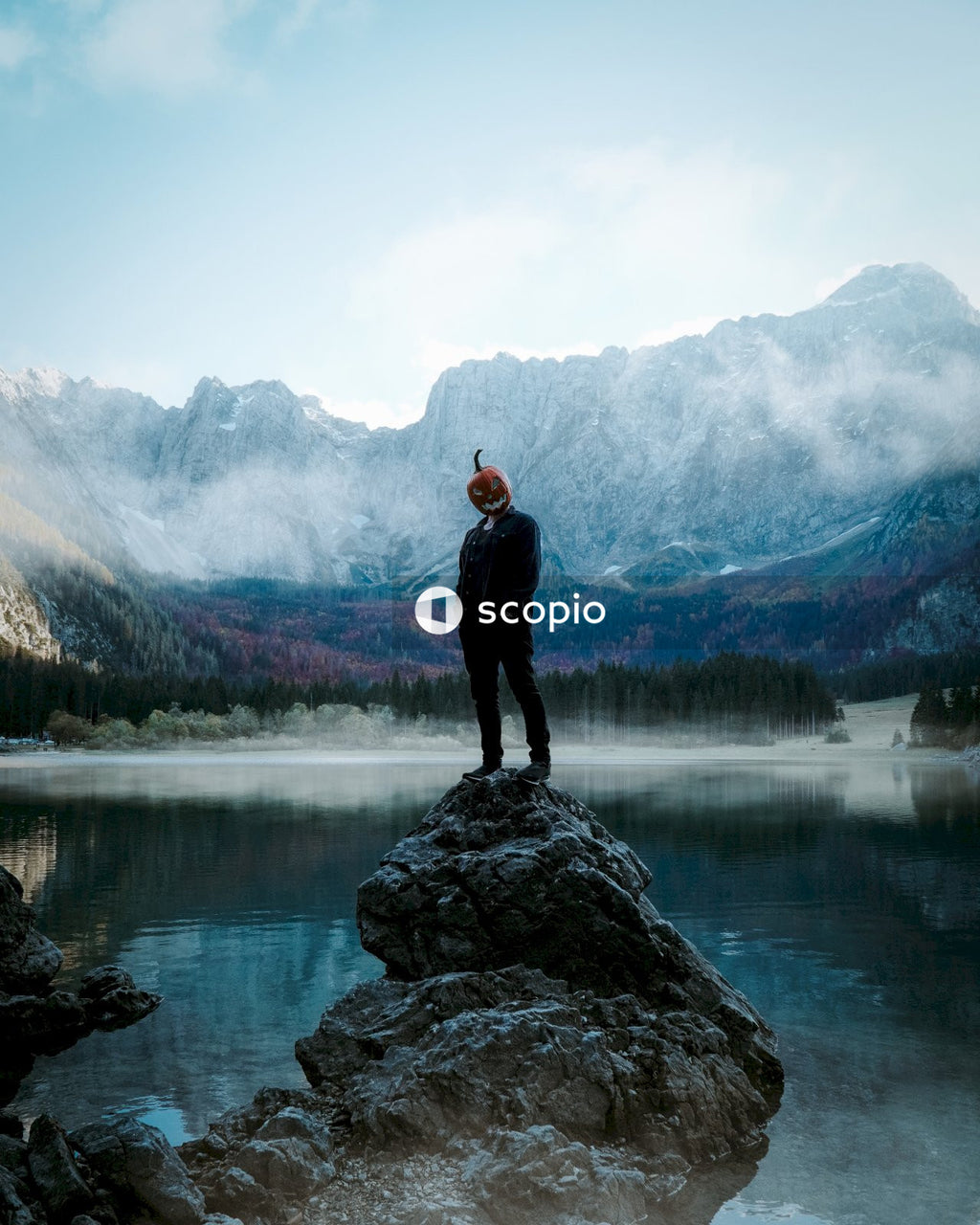 Man in black jacket standing on rock near lake
