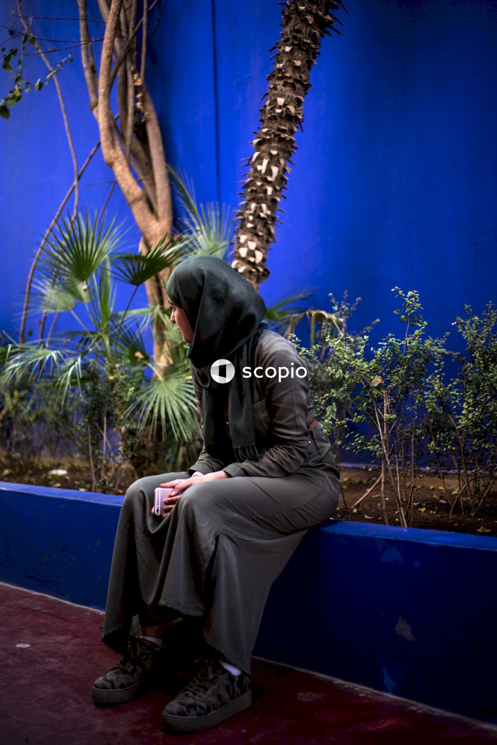 Man in black leather jacket and brown pants sitting on blue bench