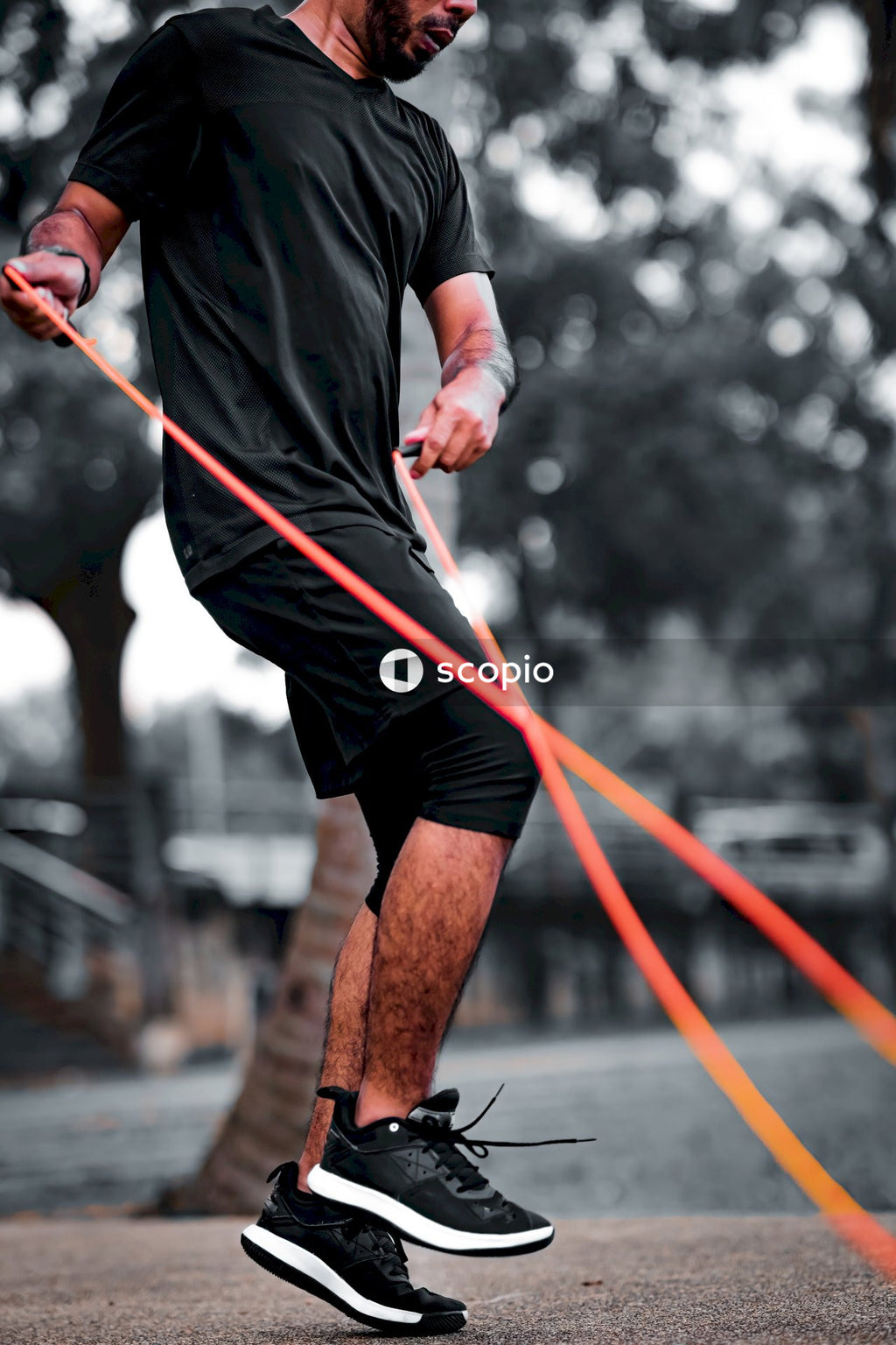 Man in black long sleeve shirt and black shorts holding red rope