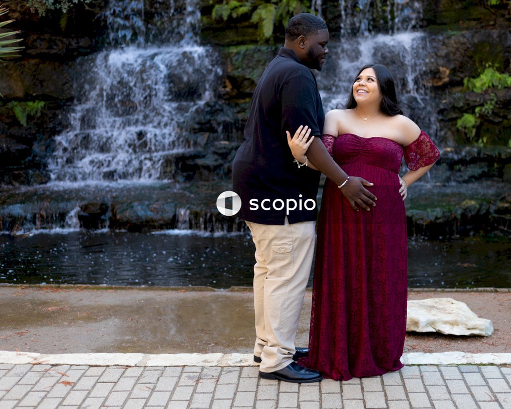 Man in black long sleeve shirt and brown pants standing beside woman in red dress
