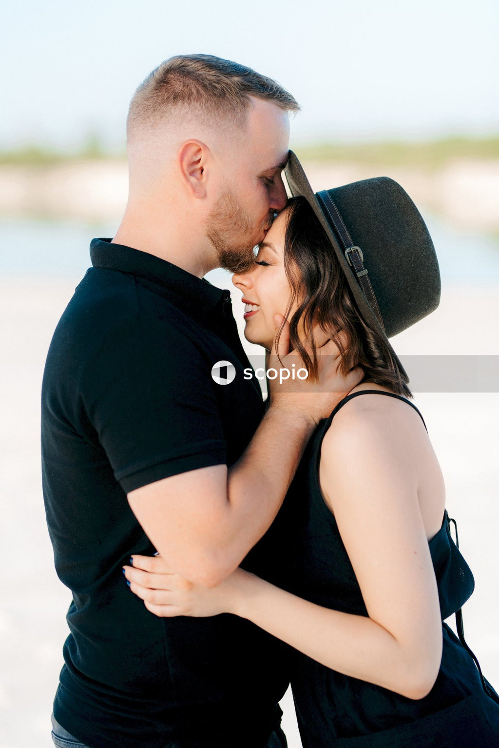 Man in black shirt kissing woman in black tank top