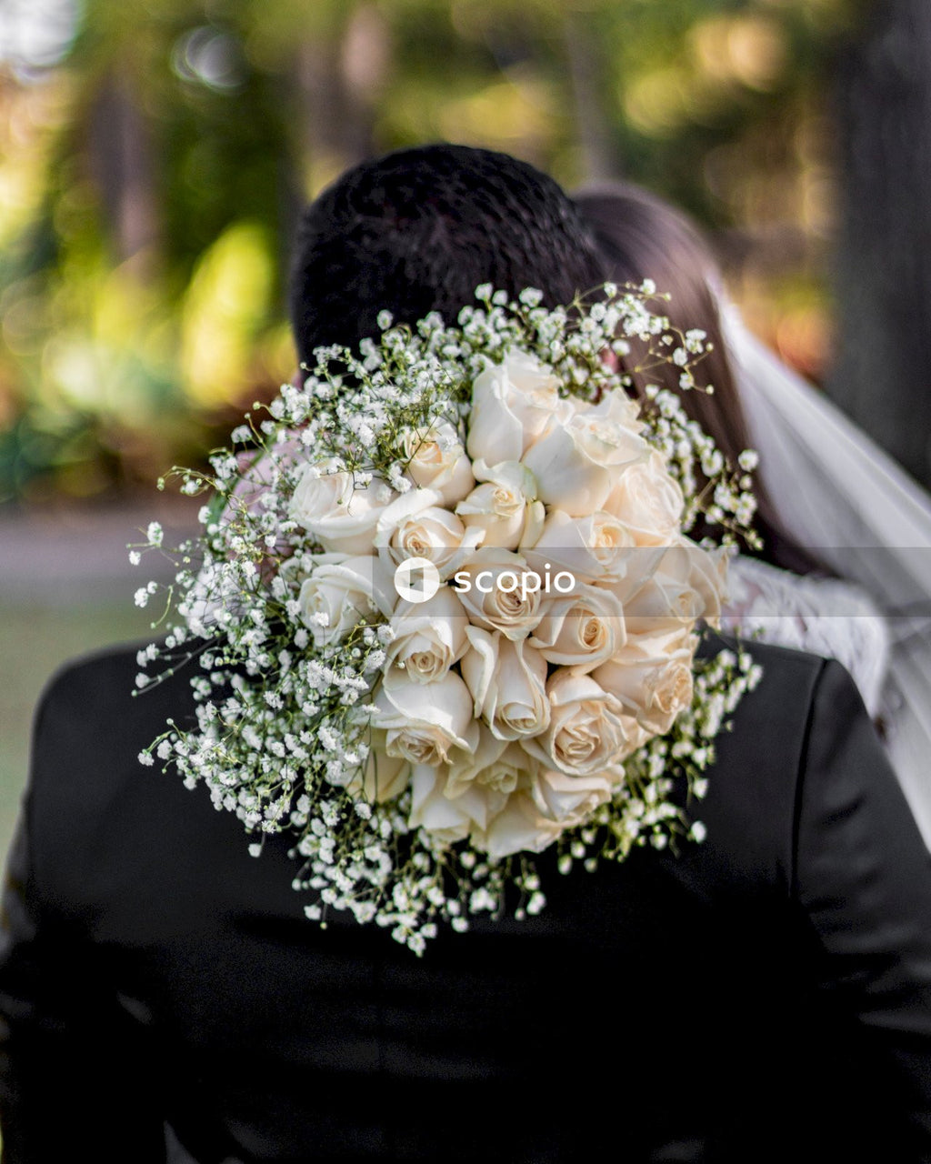 Bride holding a white flower bouquet and kissing the groom