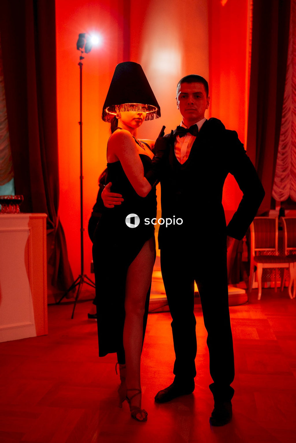 Man in black suit hugging woman in black dress