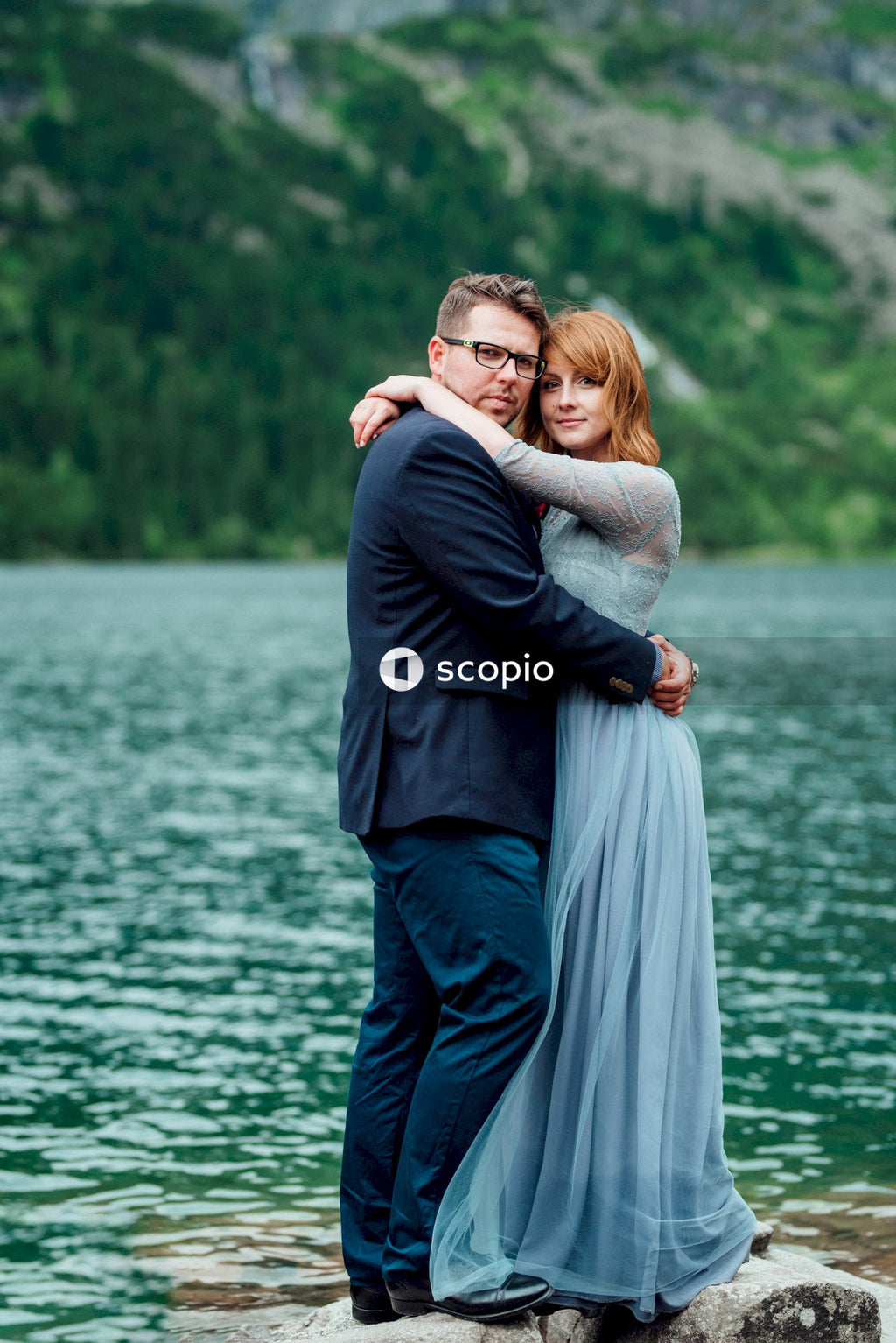Man in black suit hugging woman in white dress