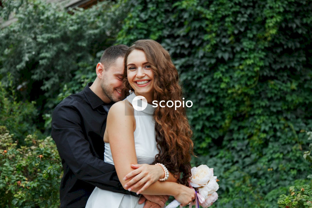 Man in black suit hugging woman in white dress