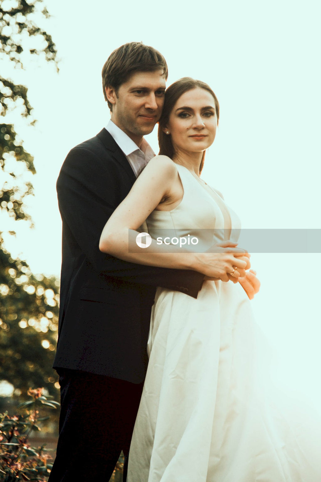 Man in black suit hugging woman in white dress