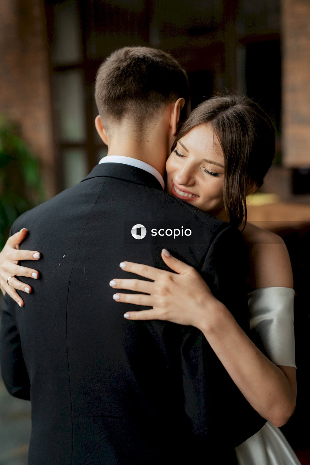 Man in black suit hugging woman in white dress