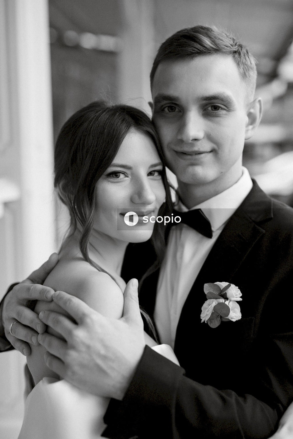Man in black suit jacket hugging woman in black tube dress
