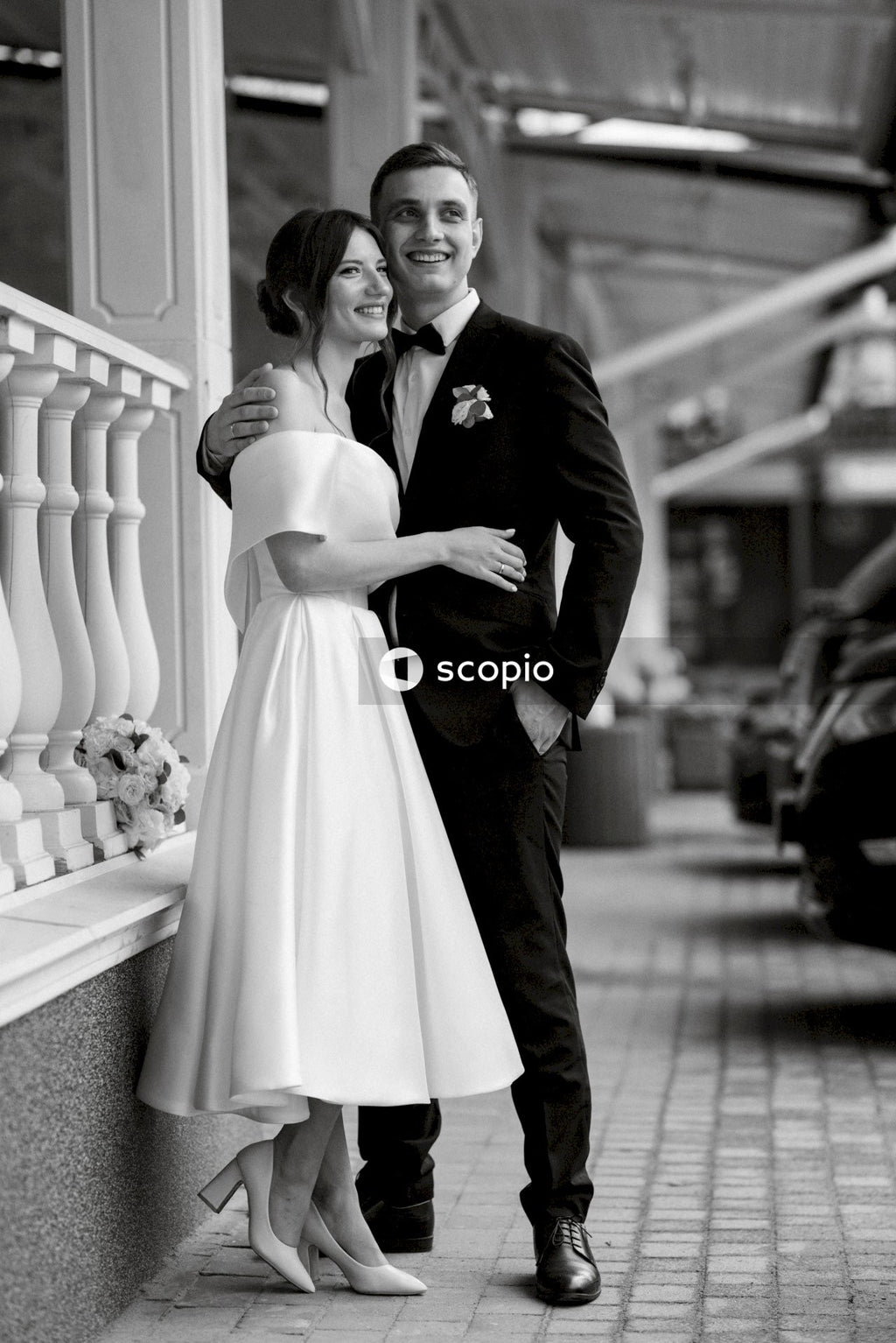 Man in black suit jacket hugging woman in white dress