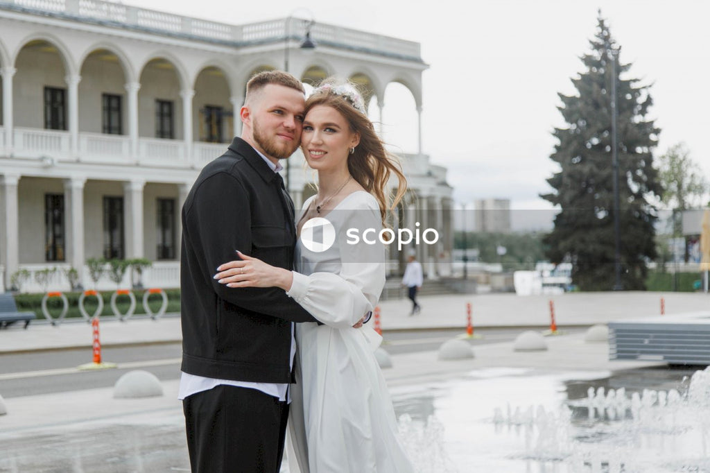 Man in black suit jacket hugging woman in white dress