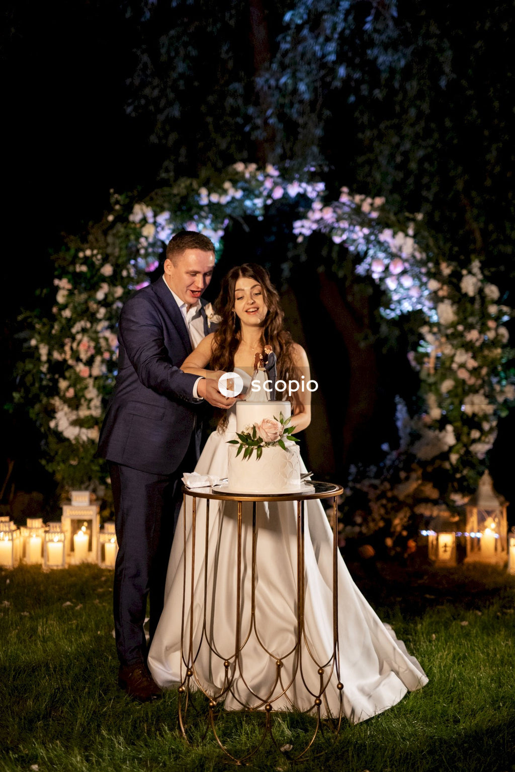 Man in black suit jacket hugging woman in white dress
