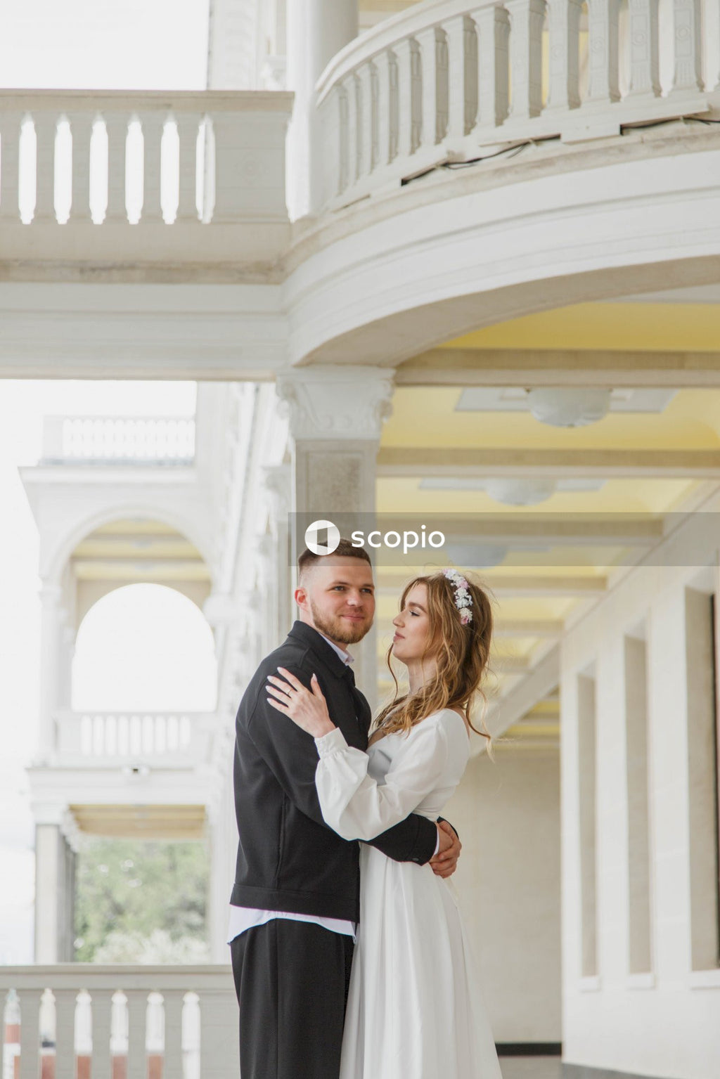 Man in black suit jacket hugging woman in white dress