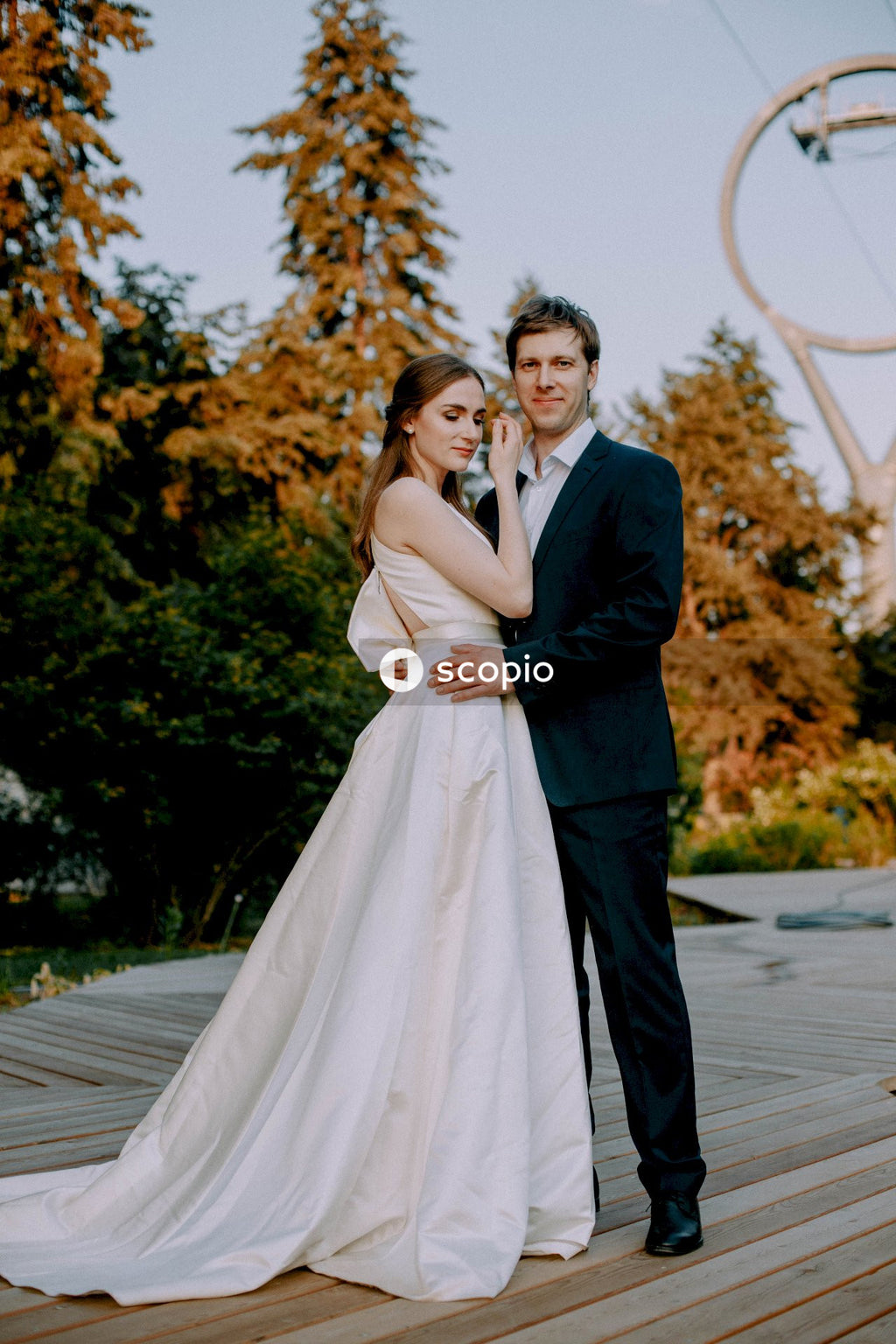 Man in black suit jacket hugging woman in white dress
