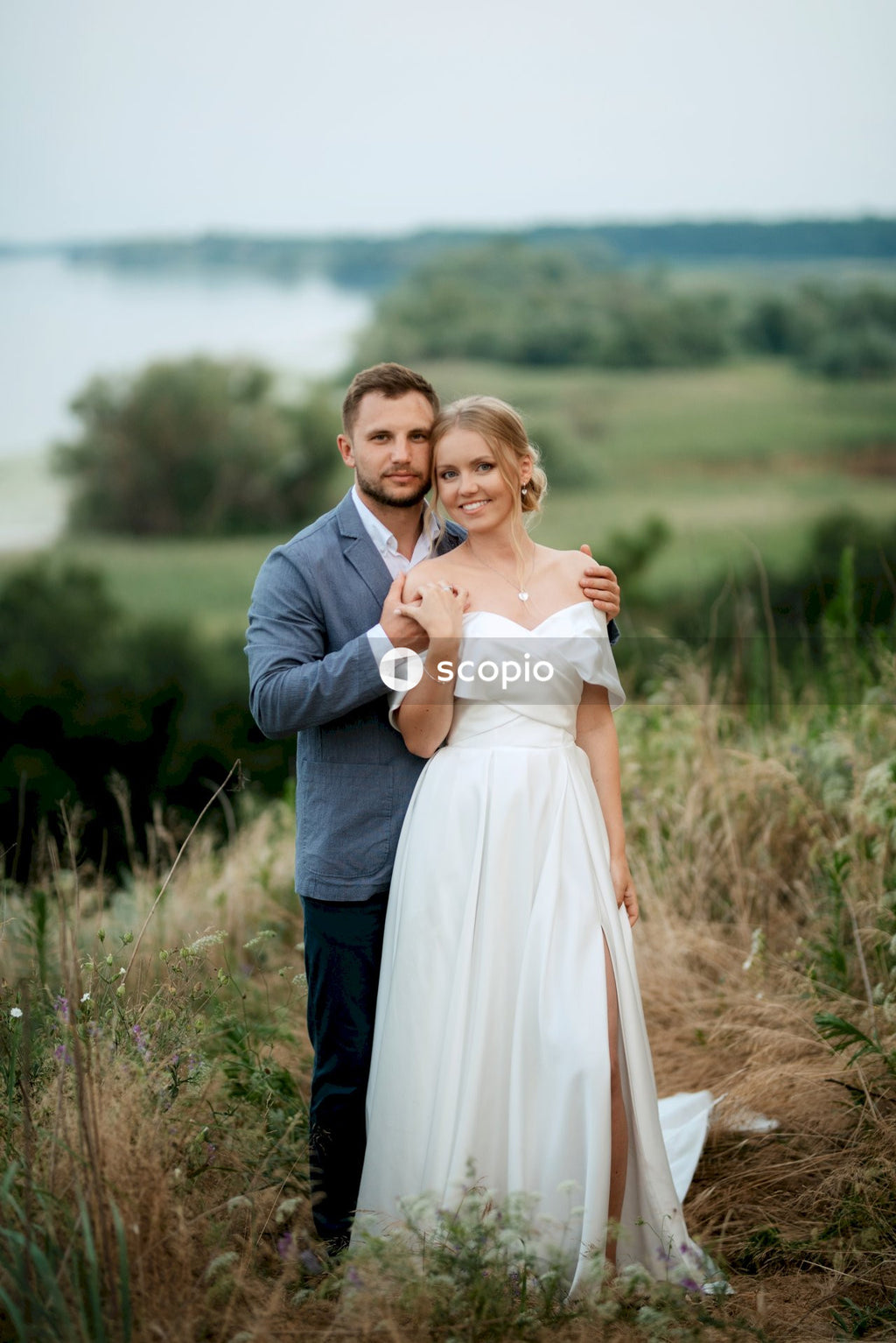 Man in black suit jacket hugging woman in white dress